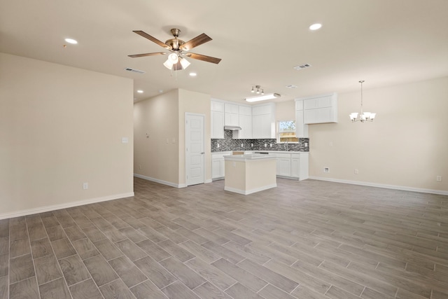 kitchen with open floor plan, ceiling fan with notable chandelier, backsplash, and visible vents