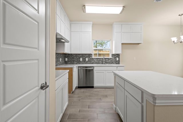 kitchen with light countertops, stainless steel dishwasher, backsplash, and a sink