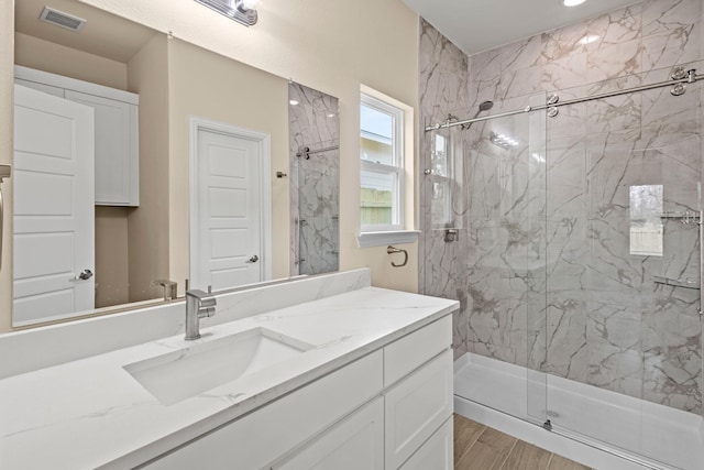 bathroom featuring visible vents, vanity, and a marble finish shower