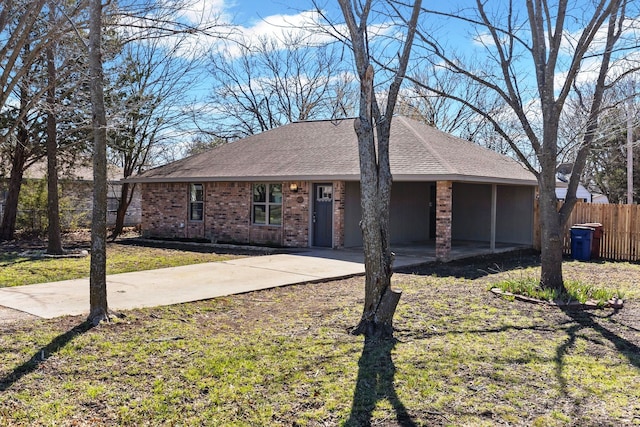 ranch-style home featuring roof with shingles, brick siding, a front lawn, and fence