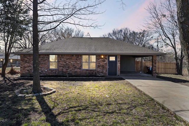 ranch-style home with driveway, a shingled roof, fence, a carport, and brick siding