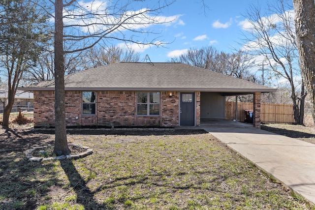 ranch-style home with driveway, roof with shingles, fence, a carport, and brick siding