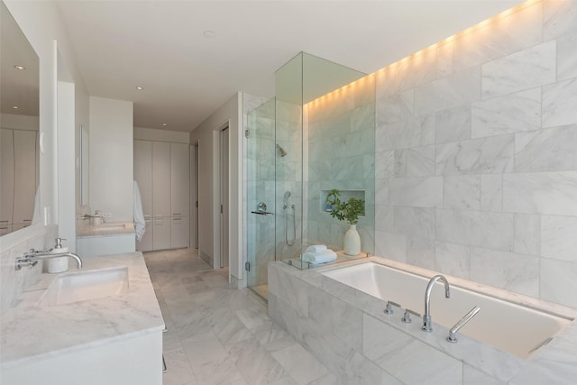 bathroom featuring double vanity, a stall shower, a garden tub, and a sink