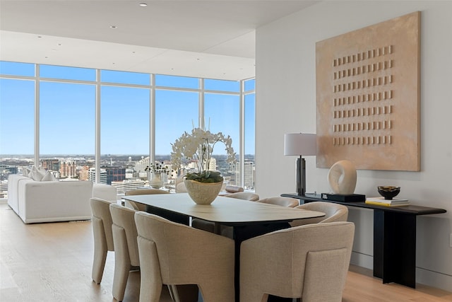 dining space featuring light wood-type flooring, expansive windows, and a city view