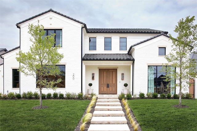 modern inspired farmhouse featuring brick siding, a front yard, and a tile roof