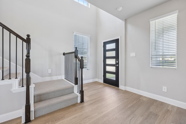 entryway with stairway, wood finished floors, and baseboards