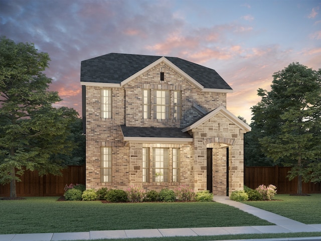 view of front of house with brick siding, a front lawn, and fence