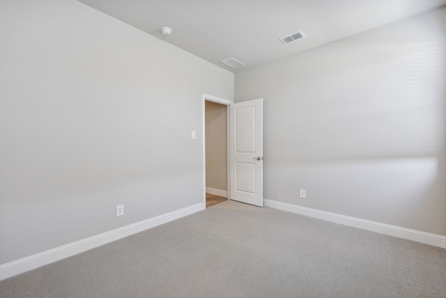 unfurnished room with visible vents, light colored carpet, and baseboards