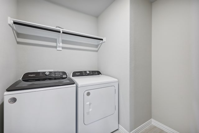 laundry room featuring light wood-type flooring, baseboards, washing machine and dryer, and laundry area