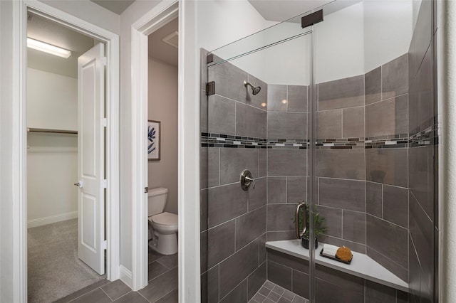 bathroom featuring a stall shower, baseboards, a spacious closet, and toilet