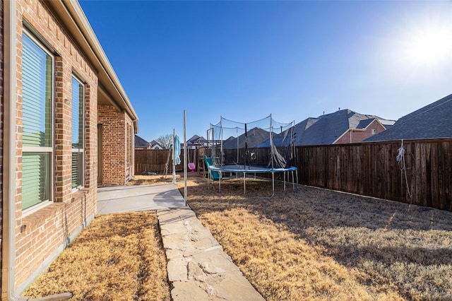 view of yard with a trampoline, a patio area, and a fenced backyard