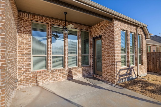 property entrance featuring brick siding, a patio area, and fence