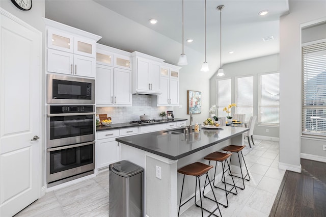 kitchen with tasteful backsplash, visible vents, a breakfast bar area, stainless steel appliances, and a sink