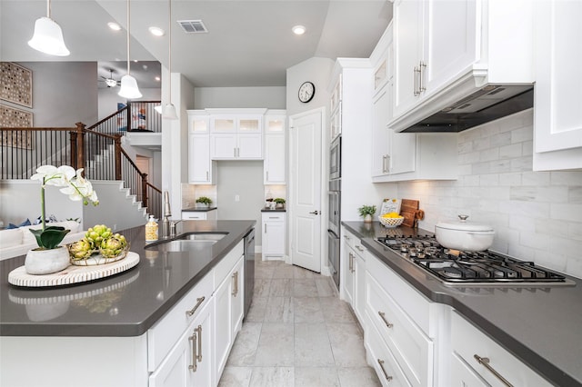 kitchen with stainless steel appliances, dark countertops, visible vents, glass insert cabinets, and a sink