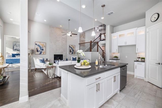 kitchen with dark countertops, visible vents, a sink, a tile fireplace, and dishwasher