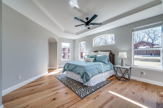 bedroom featuring ornamental molding, arched walkways, baseboards, and wood finished floors