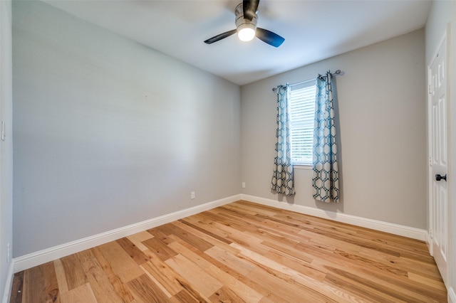 spare room featuring a ceiling fan, baseboards, and light wood finished floors