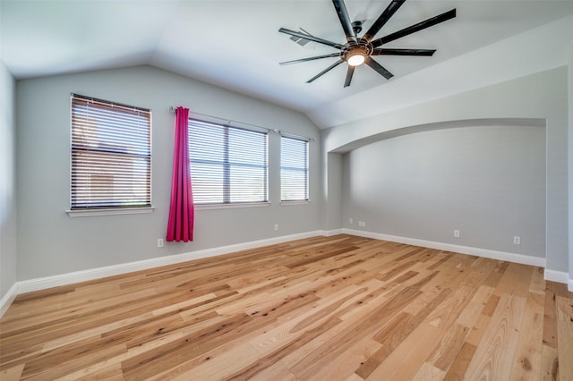 spare room with ceiling fan, light wood-style flooring, baseboards, and vaulted ceiling