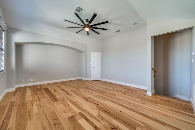 unfurnished room with light wood-type flooring, baseboards, visible vents, and arched walkways