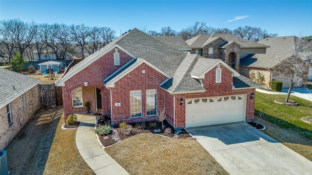 view of front facade with brick siding, a shingled roof, fence, a garage, and driveway