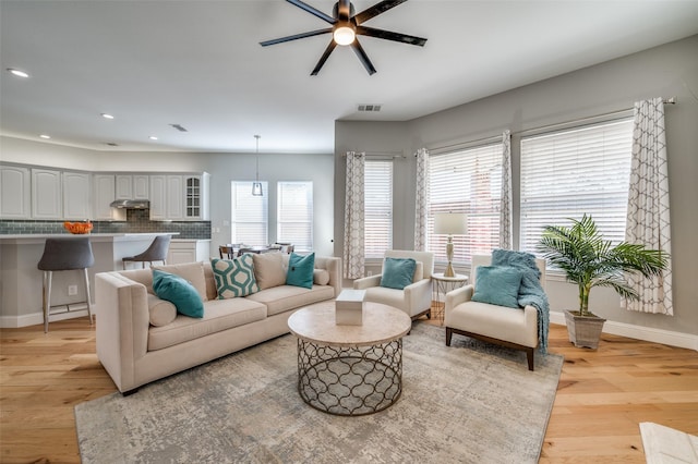 living room featuring light wood-style floors, baseboards, visible vents, and recessed lighting