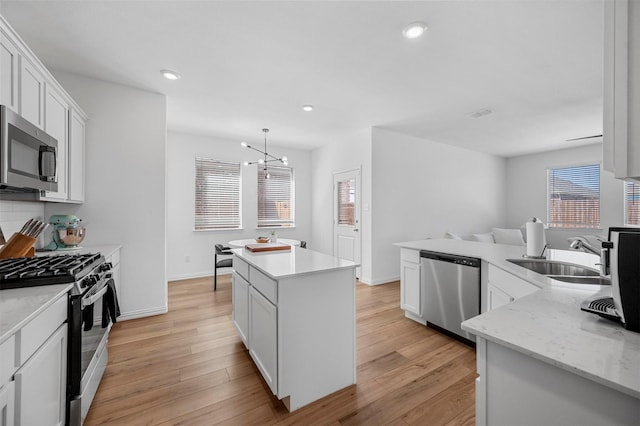 kitchen featuring recessed lighting, light wood-style flooring, appliances with stainless steel finishes, a sink, and a kitchen island