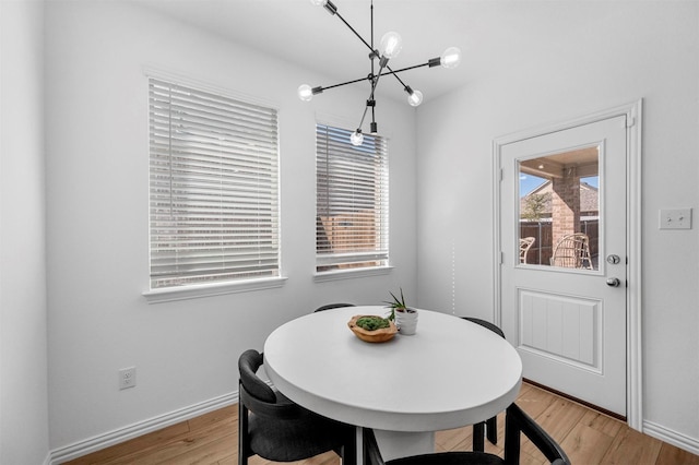 dining room with baseboards, an inviting chandelier, and light wood-style floors