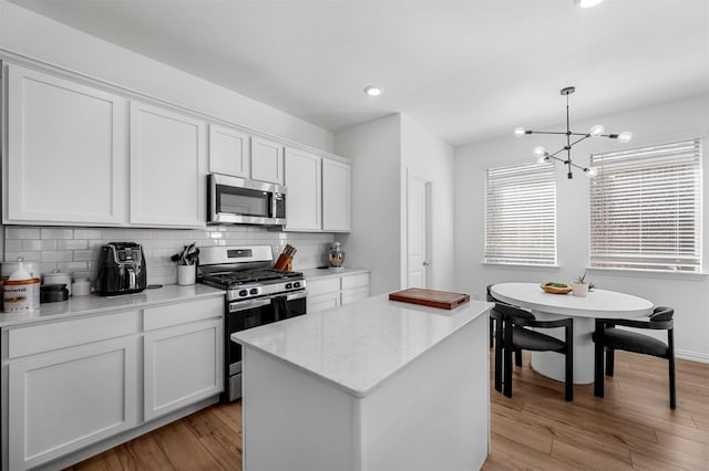 kitchen with a center island, light wood-style flooring, decorative backsplash, appliances with stainless steel finishes, and white cabinets