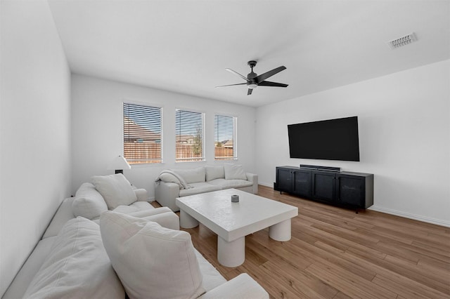 living room with a ceiling fan, light wood-type flooring, visible vents, and baseboards