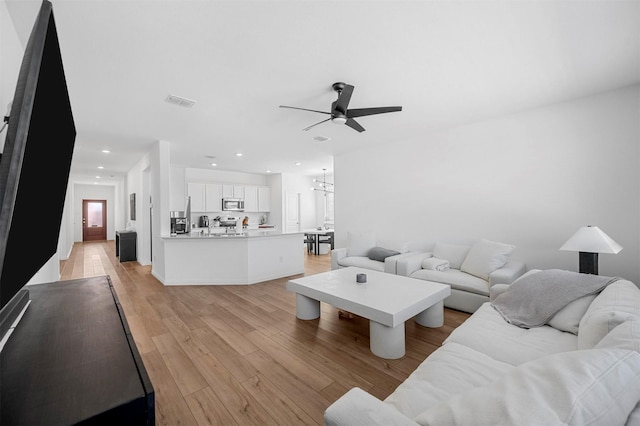 living area with light wood-type flooring, ceiling fan, visible vents, and recessed lighting