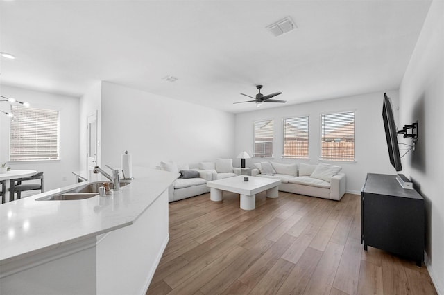 living room with visible vents, ceiling fan, light wood-style flooring, and baseboards