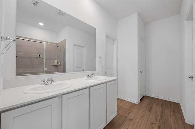 full bathroom featuring visible vents, wood finished floors, a sink, and tiled shower