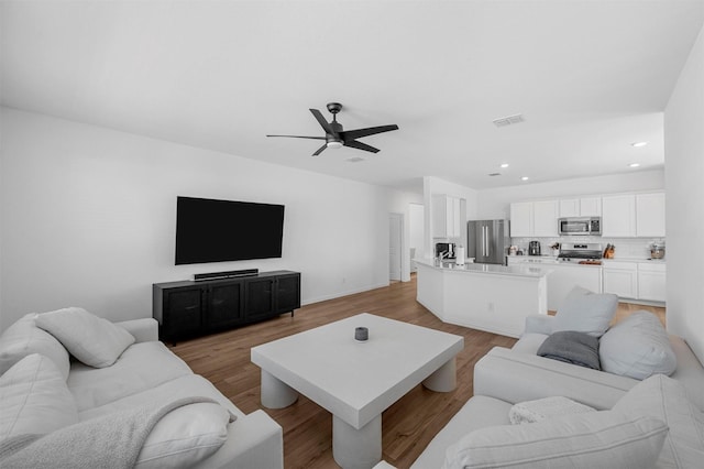 living area featuring a ceiling fan, light wood-type flooring, visible vents, and recessed lighting