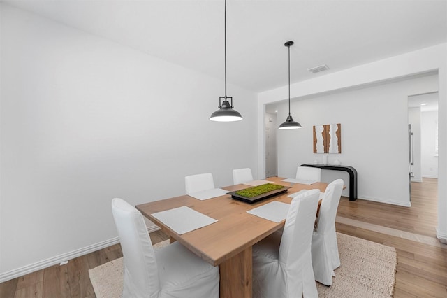 dining room with light wood finished floors, baseboards, and visible vents