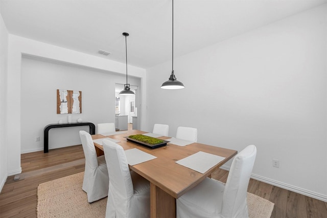 dining space with visible vents, baseboards, and wood finished floors