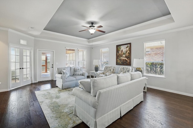 living room with dark wood-type flooring, a raised ceiling, visible vents, and baseboards