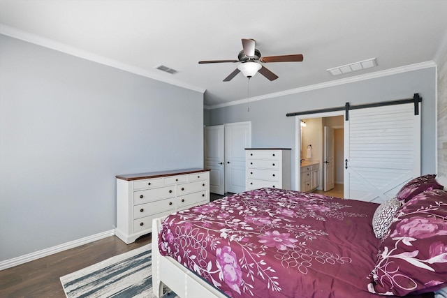 bedroom with wood finished floors, visible vents, baseboards, and a barn door