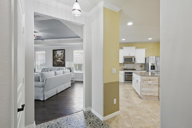 corridor with light tile patterned floors, baseboards, a raised ceiling, ornamental molding, and recessed lighting