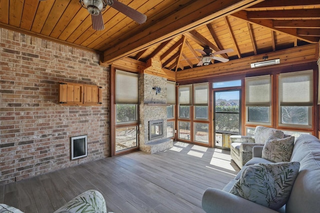 unfurnished sunroom featuring vaulted ceiling with beams, wooden ceiling, ceiling fan, and a fireplace