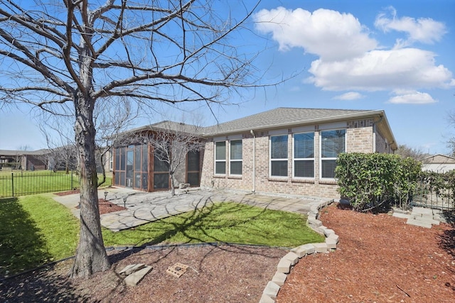 back of property featuring a yard, fence, a patio, and brick siding