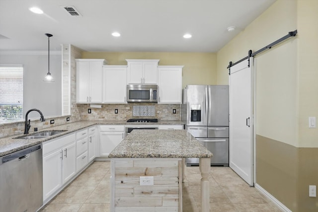 kitchen featuring a barn door, a sink, visible vents, appliances with stainless steel finishes, and backsplash