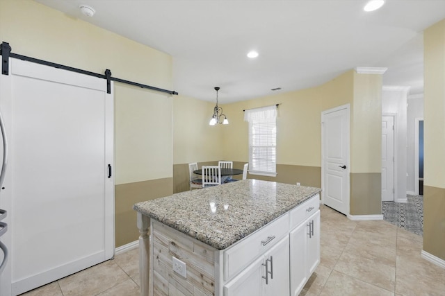 kitchen featuring light tile patterned floors, a barn door, a kitchen island, white cabinets, and light stone countertops