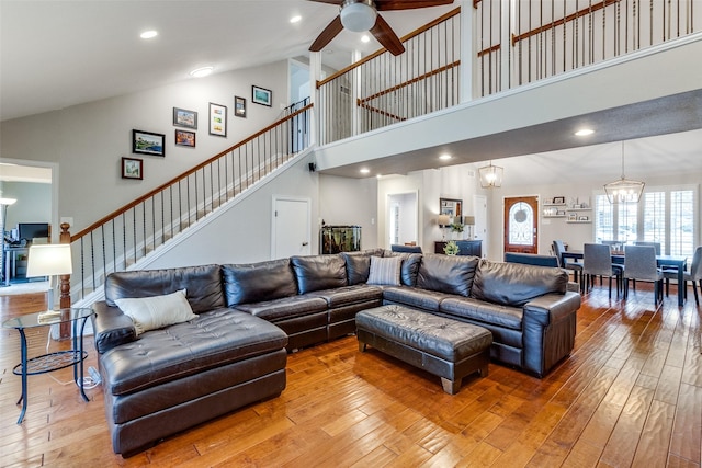 living room featuring ceiling fan with notable chandelier, light wood-type flooring, and stairs