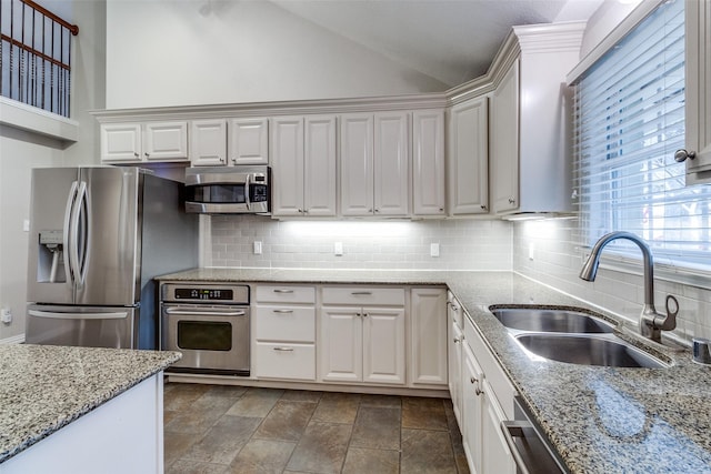 kitchen featuring appliances with stainless steel finishes, white cabinets, a sink, and backsplash