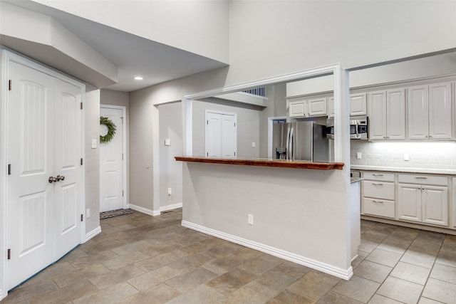 kitchen with white cabinetry, baseboards, light countertops, appliances with stainless steel finishes, and backsplash