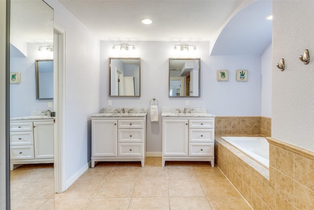 full bath featuring a bath, vanity, a textured ceiling, and tile patterned floors