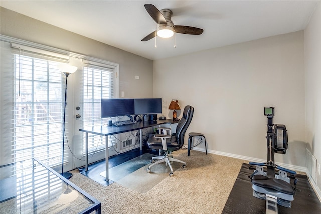 carpeted office space featuring ceiling fan and baseboards