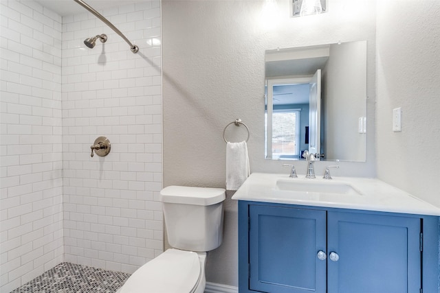 bathroom featuring visible vents, a textured wall, toilet, a tile shower, and vanity