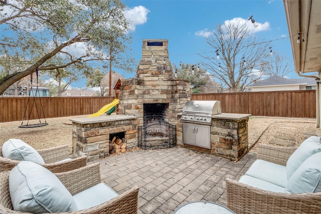 view of patio with exterior fireplace, a fenced backyard, and grilling area