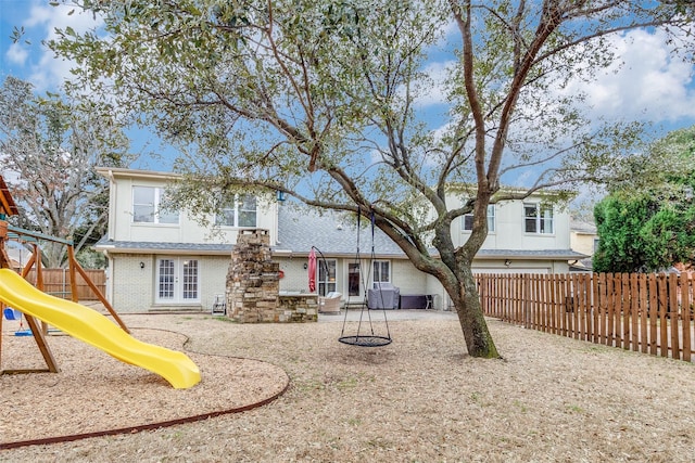 back of property with a patio, a playground, fence private yard, brick siding, and french doors